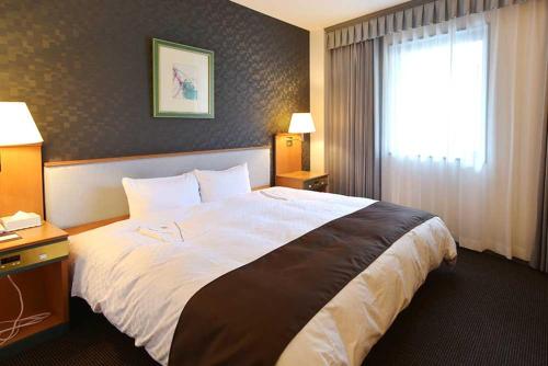 a hotel room with a large bed and a window at Blossom Hotel Hirosaki in Hirosaki