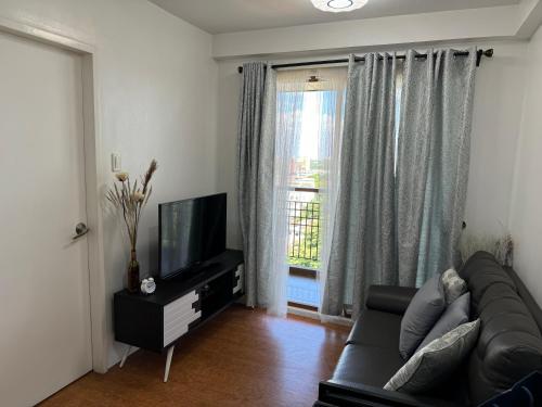 un salon avec un canapé et une télévision dans l'établissement cozy2ndhomeFRM, à Manille
