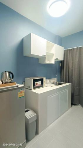 a kitchen with white cabinets and a sink at Fuengfa Room in Khlong Luang