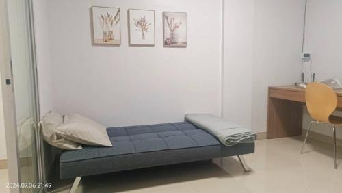 a blue bench in a room with a desk and three pictures at Fuengfa Room in Khlong Luang