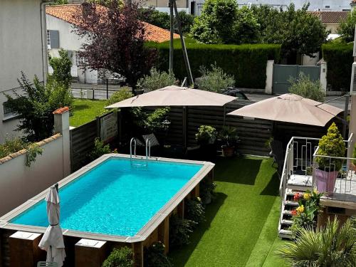 einen Pool im Garten mit Sonnenschirmen in der Unterkunft Logis Le Passiflore Cognac in Châteaubernard