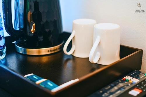 two coffee cups and a remote control on a table at The Ivy Lake in Anuradhapura