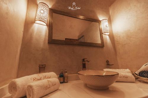 a bathroom with a sink and a mirror and towels at Riad Aslal in Marrakech