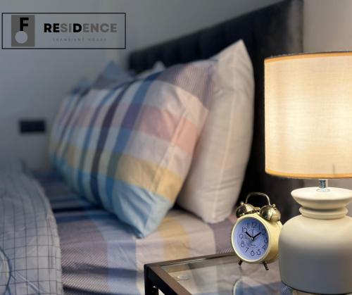 a alarm clock on a table next to a bed at F Residence Transient House in Cabanatuan
