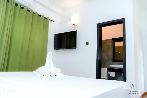 a room with a bed and a tv on the wall at The Ivy Lake in Anuradhapura