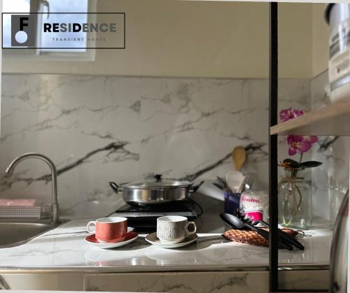 a kitchen counter with two cups and a pot on a stove at F Residence Transient House in Cabanatuan