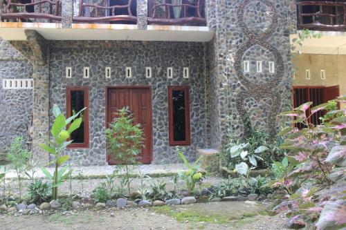 a stone building with a red door and some plants at Rinte Green Village & Bukit Lawang Jungle Trekking in Bukit Lawang