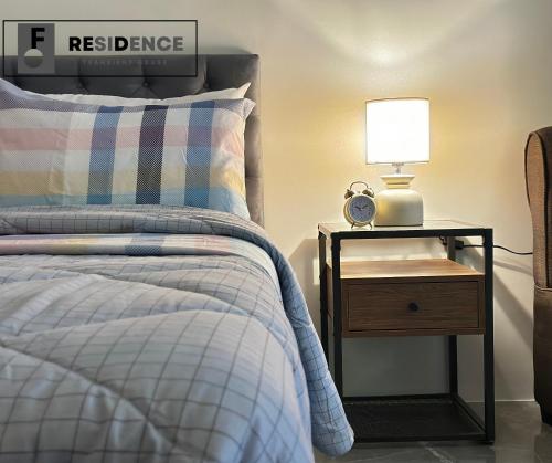 a bedroom with a bed and a nightstand with a lamp at F Residence Transient House in Cabanatuan