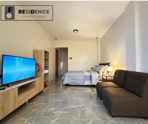 a living room with a tv and a bed at F Residence Transient House in Cabanatuan