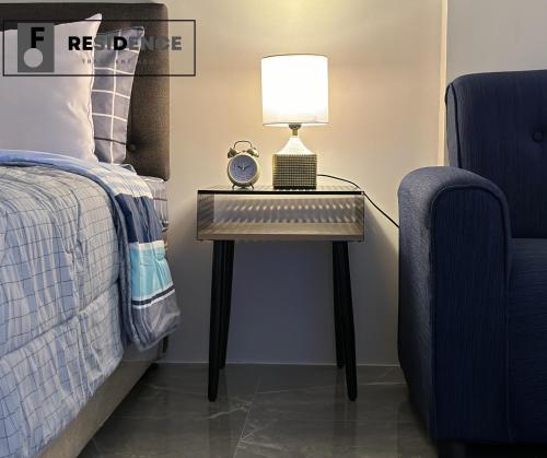 a bedside table with a lamp and a chair at F Residence Transient House in Cabanatuan