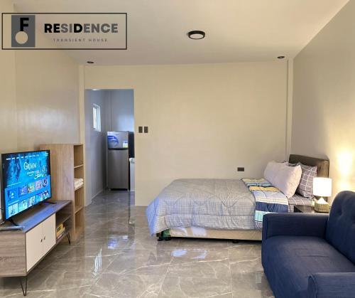 a bedroom with a bed and a tv and a couch at F Residence Transient House in Cabanatuan