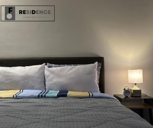 a bedroom with a bed with white pillows and a lamp at F Residence Transient House in Cabanatuan
