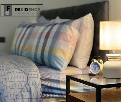 a bedroom with a bed and a table with a alarm clock at F Residence Transient House in Cabanatuan