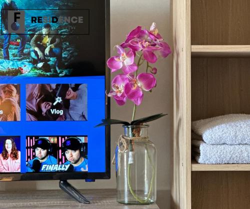 a vase with pink flowers in front of a tv at F Residence Transient House in Cabanatuan