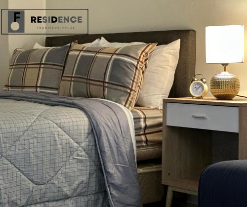 a bedroom with a bed and a nightstand with a clock at F Residence Transient House in Cabanatuan