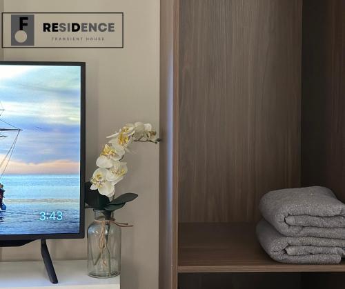 a vase with flowers in a room with a tv at F Residence Transient House in Cabanatuan