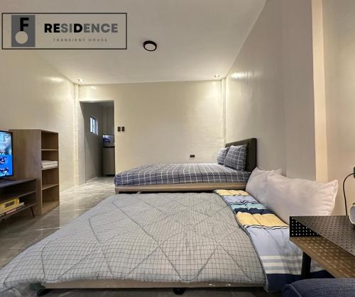 a bedroom with two beds and a tv in it at F Residence Transient House in Cabanatuan