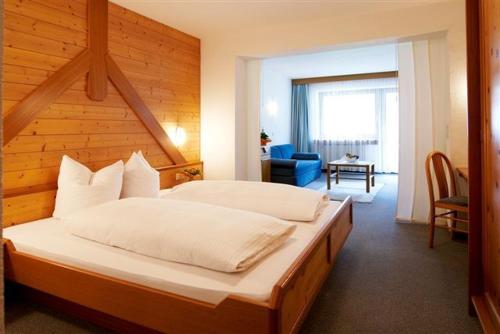 ein Schlafzimmer mit einem großen Bett und einer Holzwand in der Unterkunft Hotel Silvretta in Sankt Gallenkirch