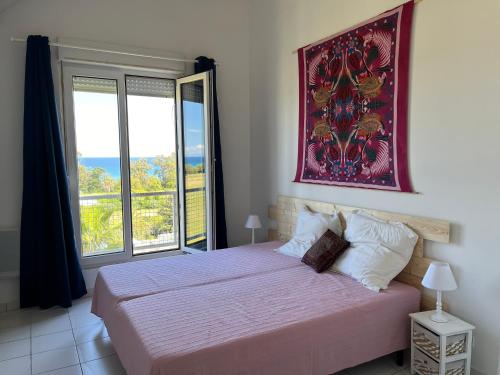 une chambre avec un lit et une grande fenêtre dans l'établissement Duplex vue mer à Piana Verde Canale-di-verde, à Canale-di-Verde