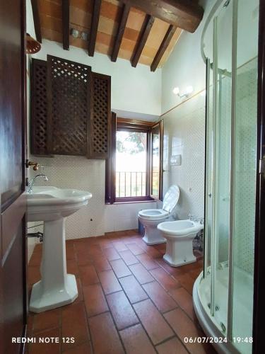 a bathroom with two toilets and a sink and a shower at La casa dei breton in Magione