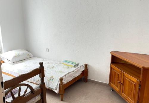 a small bedroom with a bed and a wooden dresser at Hostel Flash in Ulcinj