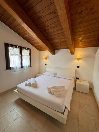 a large white bed in a room with wooden ceilings at Nura's - Casa Le Ginestre in Alghero