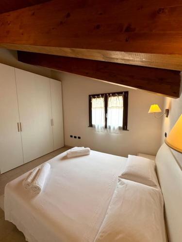 a bedroom with a large white bed and a window at Nura's - Casa Le Ginestre in Alghero
