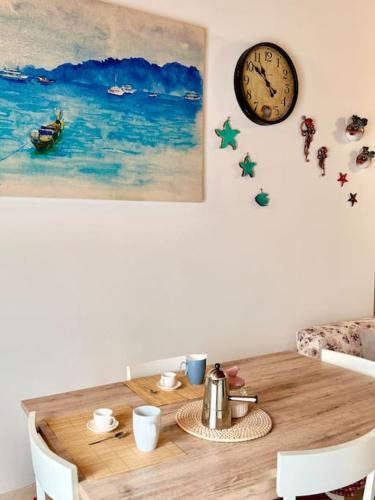 a dining room table with a clock on the wall at Nura's - Casa Le Ginestre in Alghero