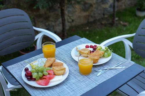 a table with two plates of fruit and orange juice at Comfort Rooms Pogradec in Pogradec