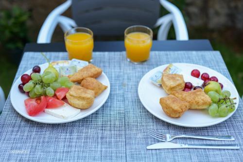 two plates of food on a table with fruit and orange juice at Comfort Rooms Pogradec in Pogradec