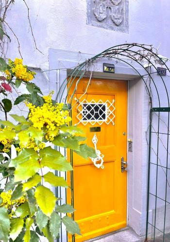 an orange door on a building with yellow flowers at Zurich near the lake single room in historical house shared Bathroom in Kilchberg