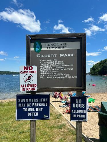 a sign at a beach with signs on it at LONG LAKE RETREAT- Hot tub, Pool table, Firepit in Traverse City