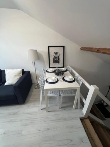 un salon avec une table et des chaises blanches dans l'établissement Appartement Neuf,épuré et bien placé, à Mulhouse