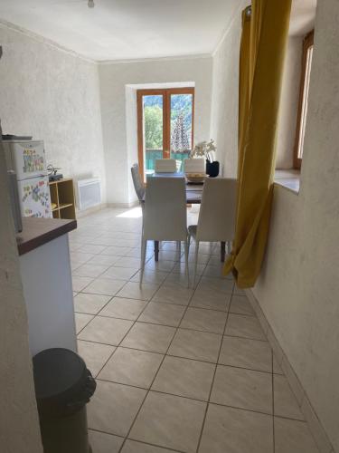 une cuisine et une salle à manger avec une table et des chaises dans l'établissement logement appartement dansMaison de pays, à Saint-Martin-de-Queyrières