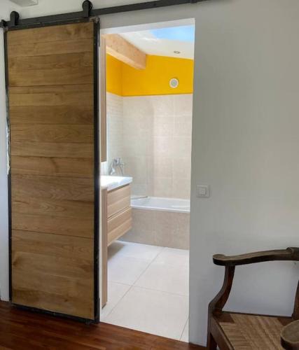 La salle de bains est pourvue d'une porte en bois et d'une baignoire. dans l'établissement Espace Bergerie La maison d'Hélène, à Peille