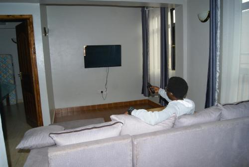 a boy sitting on a couch in a living room at CH Apartment Hotel in Kisii