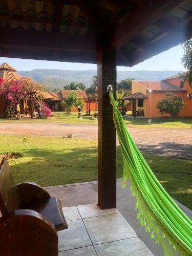 a hammock on a porch with a view of a yard at Pousada e restaurante Jardim do Cerrado MT in Nobres