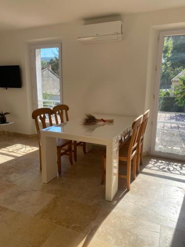une table à manger blanche avec des chaises et une fenêtre dans l'établissement Appartement climatisé proche Marseille,Aix, à La Destrousse