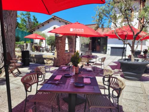 a wooden table with chairs and a red umbrella at Tenuta del Duca Fiumicino Locanda e Hostaria Guest House in Fiumicino