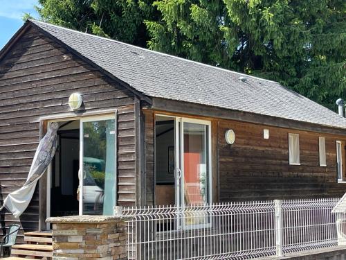 a small wooden house with a fence in front of it at Chalet de la plage in Arvieu
