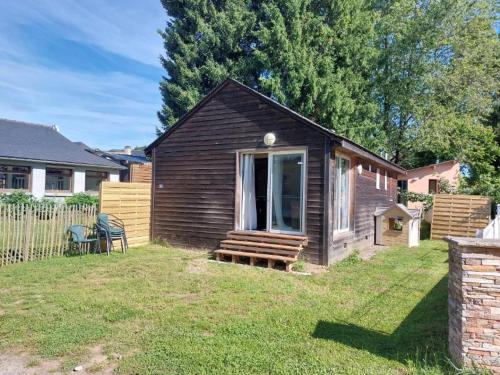 a small brown house with a bench in a yard at Chalet de la plage in Arvieu