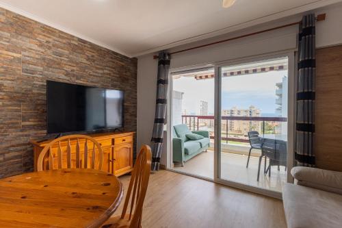 un salon avec une télévision à écran plat et une table dans l'établissement FABULOSO APARTAMENTO CON VISTAS AL MAR, à Playa de Gandia