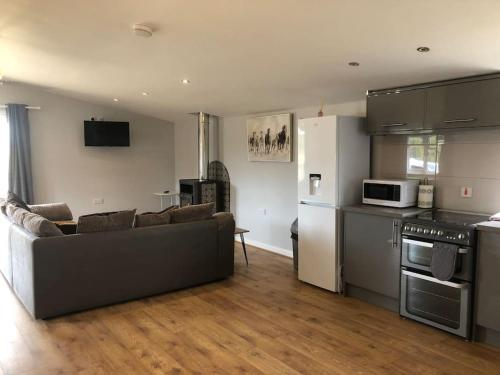 a living room with a couch and a kitchen at Nightingale Lodge - Adults Only in Lackford