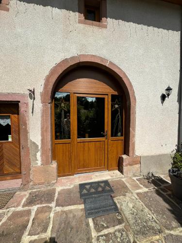 une porte en bois d'un bâtiment avec une arche dans l'établissement GÎTE EMERAUDE, à Plaine