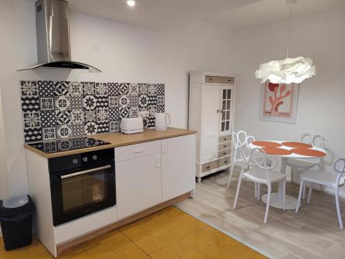 une cuisine avec une cuisinière et une table avec des chaises dans l'établissement Petite maison entre mer et montagne, à Céret