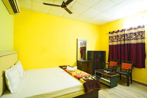 a yellow room with a bed and a table at Sea Smile Inn in Mandarmoni