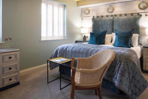 a bedroom with a bed with a chair and a table at Talland Bay Hotel, Looe in Talland