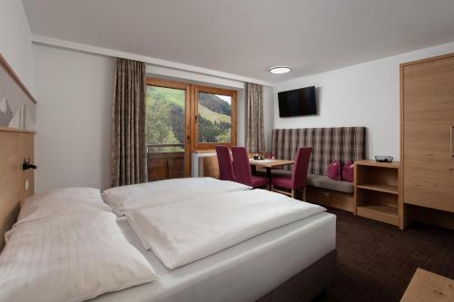 a bedroom with a bed and a table and a window at Landhaus Gappmaier in Saalbach Hinterglemm