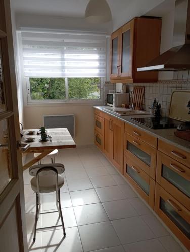 une cuisine avec des armoires en bois, une table et une fenêtre dans l'établissement Bel appartement bord de mer à St Cyr Sur Mer, à Saint-Cyr-sur-Mer