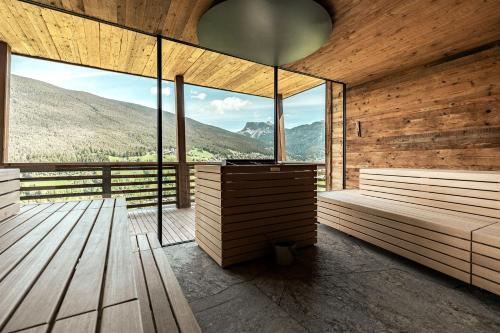 a room with two benches and a large window at Hotel Niblea Dolomites in Ortisei